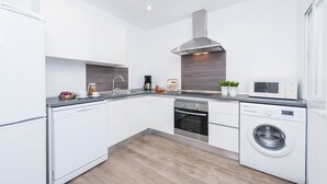 Eine moderne Küche mit weißen Schränken, Edelstahlgeräten und einem eingebauten Backofen.