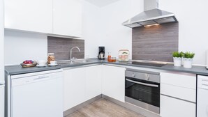 Eine moderne Küche mit weißen Schränken, einer Edelstahl-Dunstabzugshaube, einem Geschirrspüler und einem eingebauten Backofen.