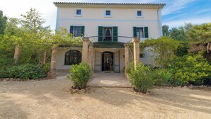 A two-story building with a covered entrance, surrounded by greenery. - CAS PILOT - Villa with private pool in Santa Maria del Cami. Free WiFi (Santa Maria)