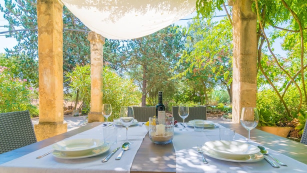 An outdoor dining area with a table set for two, surrounded by wicker chairs, under a canopy. - CAS PILOT - Villa with private pool in Santa Maria del Cami. Free WiFi (Santa Maria)