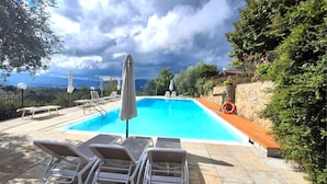 A swimming pool with lounge chairs and umbrellas, surrounded by stone walls and greenery. - Nice apartment for 6 people with pool, WIFI and TV (Canova)