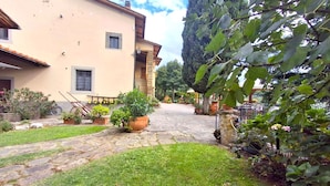 A courtyard with a stone pathway leading to a building with a tiled roof. There are potted plants and a bicycle in the foreground. - Nice apartment for 6 people with pool, WIFI and TV (Canova)