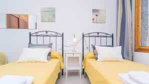 Ein Doppelzimmer mit zwei Betten, einem Nachttisch und einer Wandlampe.