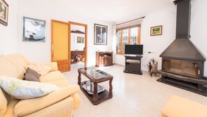 Ein Wohnzimmer mit einer Couch, einem Glastisch, einem Kamin und gerahmten Bildern an den Wänden.