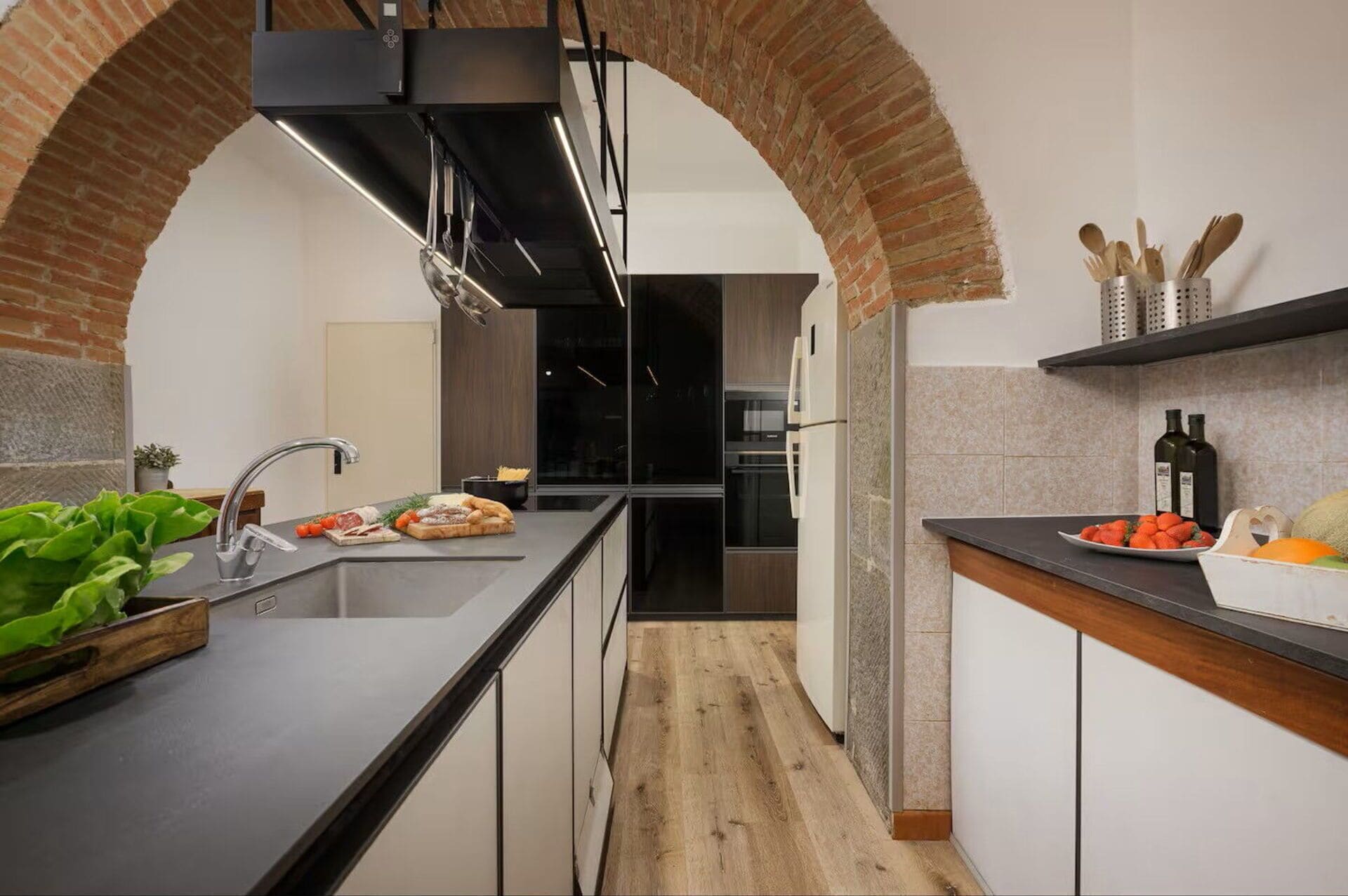 A modern kitchen with a black countertop, a sink, a stove, and a refrigerator.