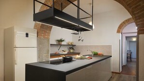 A modern kitchen with a central island, built-in appliances, and an exposed brick wall. - Stunning private villa with hot tub, private pool, WIFI, A/C and panoramic view, close to Cortona (Fratticciola)