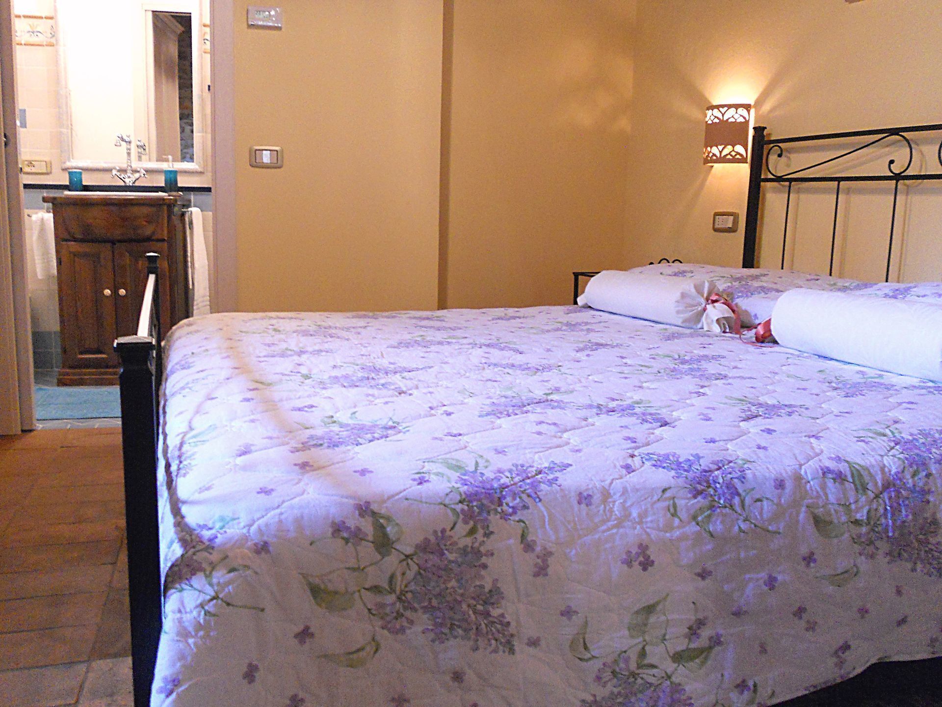 Una camera da letto con un letto, un comodino, uno specchio e una lampada a parete.