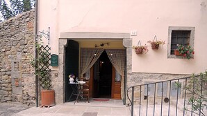 A stone building with a wooden door, a small table with a vase, and a chair outside. - Nice apartment for 2 people with WIFI and TV (Cortona)
