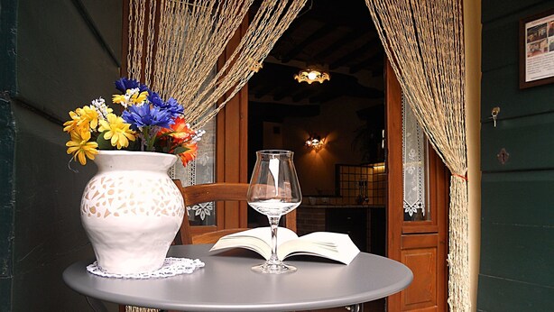 A table with a vase of flowers, a wine glass, and an open book. - Nice apartment for 2 people with WIFI and TV (Cortona)