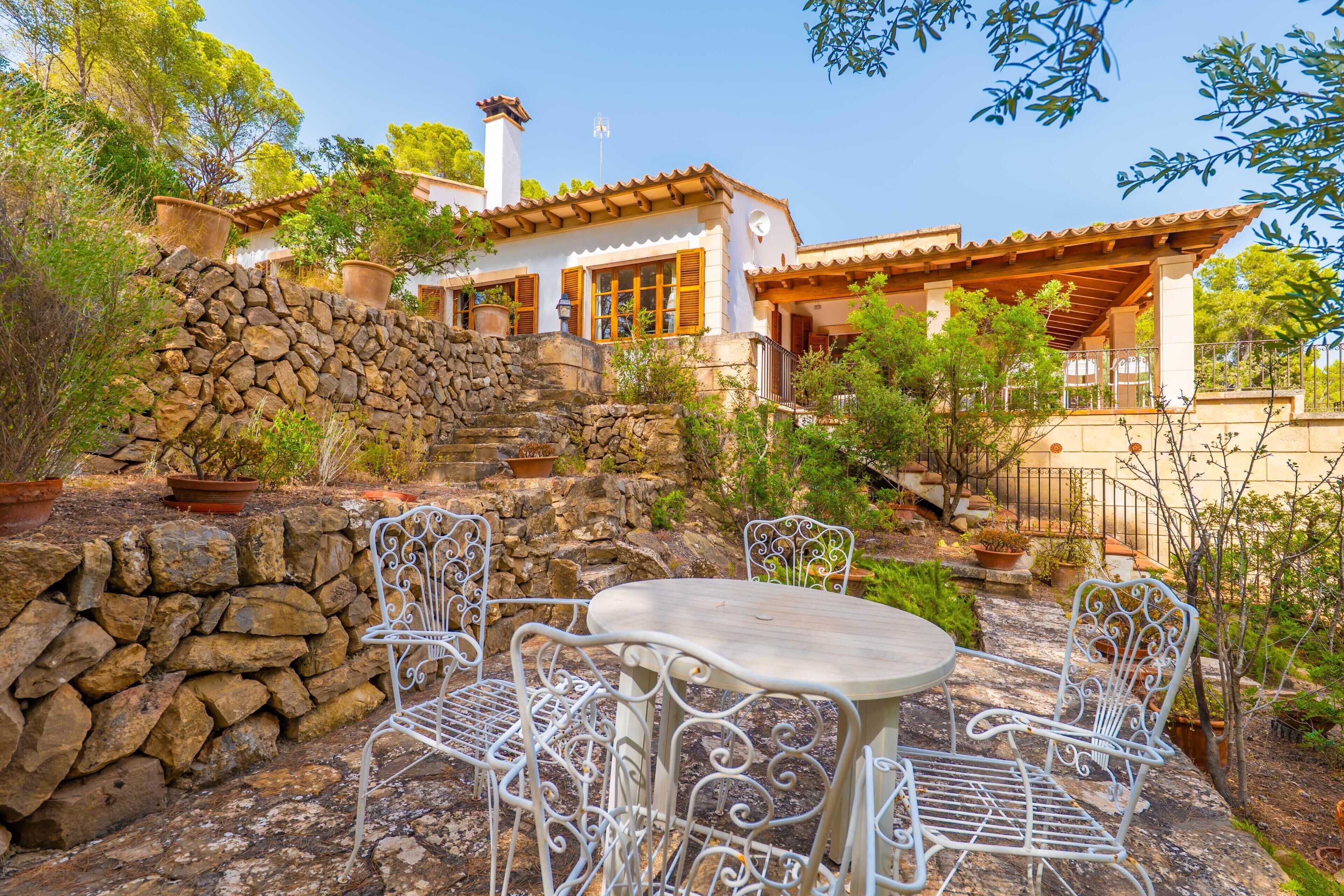 A stone wall, outdoor seating, and a building with a tiled roof.