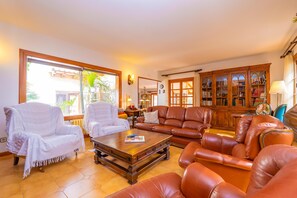 A spacious living room with leather sofas, a coffee table, and a wooden cabinet with glass doors. - CAN PERE VELL - Villa with private pool in ANDRATX. Free WiFi (Andratx)