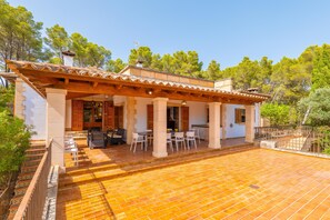 A villa with a tiled patio, outdoor seating, and a pergola.