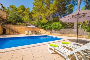 A swimming pool with a stone staircase leading up to a building, surrounded by trees and a patio area with lounge chairs and an umbrella. - CAN PERE VELL - Villa with private pool in ANDRATX. Free WiFi (Andratx)