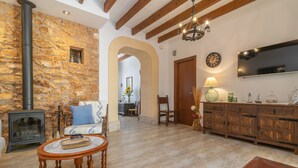 Un salon chaleureux avec un mur en pierre, une cheminée, un canapé, une table basse et un meuble en bois.