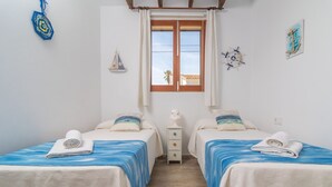 Une chambre avec deux lits, une fenêtre, une table de chevet et des éléments décoratifs sur les murs.