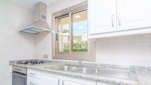 Une cuisine moderne avec des meubles blancs, un évier en acier inoxydable et une cuisinière à gaz.