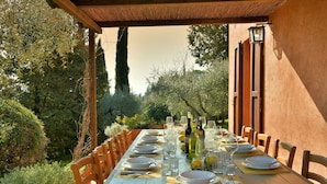 An outdoor dining area with a long table set for a meal, surrounded by wooden chairs, and a pergola overhead. - Stunning private villa for 12 guests with private pool, WIFI, TV, terrace and panoramic view (Montelopio)
