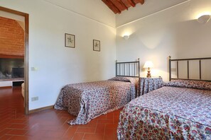 Two single beds with floral-patterned bedspreads, a brick fireplace, and a simple design.