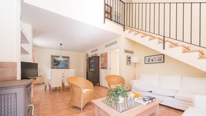 A living room with a white sofa, wicker chairs, a coffee table, a TV, and a staircase. - EL PINAR  - Villa with private pool in Cala Sant Vicenç. Free WiFi (Pollen��a)