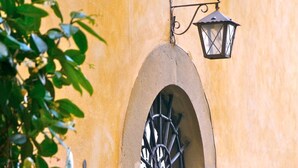 A building with an arched doorway, a hanging lantern, and a hanging flower basket. - Lovely apartment for 3 people with hot tub, WIFI, A/C and TV (Cortona)