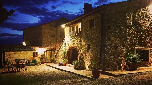 Un edificio de piedra con patio, mesas al aire libre y plantas en macetas.