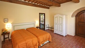 Un dormitorio con cama doble, una mesita de noche con lámpara, un armario y una puerta que da al baño.