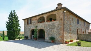 A stone building with a tiled roof, two arches, and potted plants.