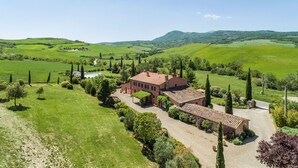 A rural property with a large house surrounded by lush green fields and rolling hills.