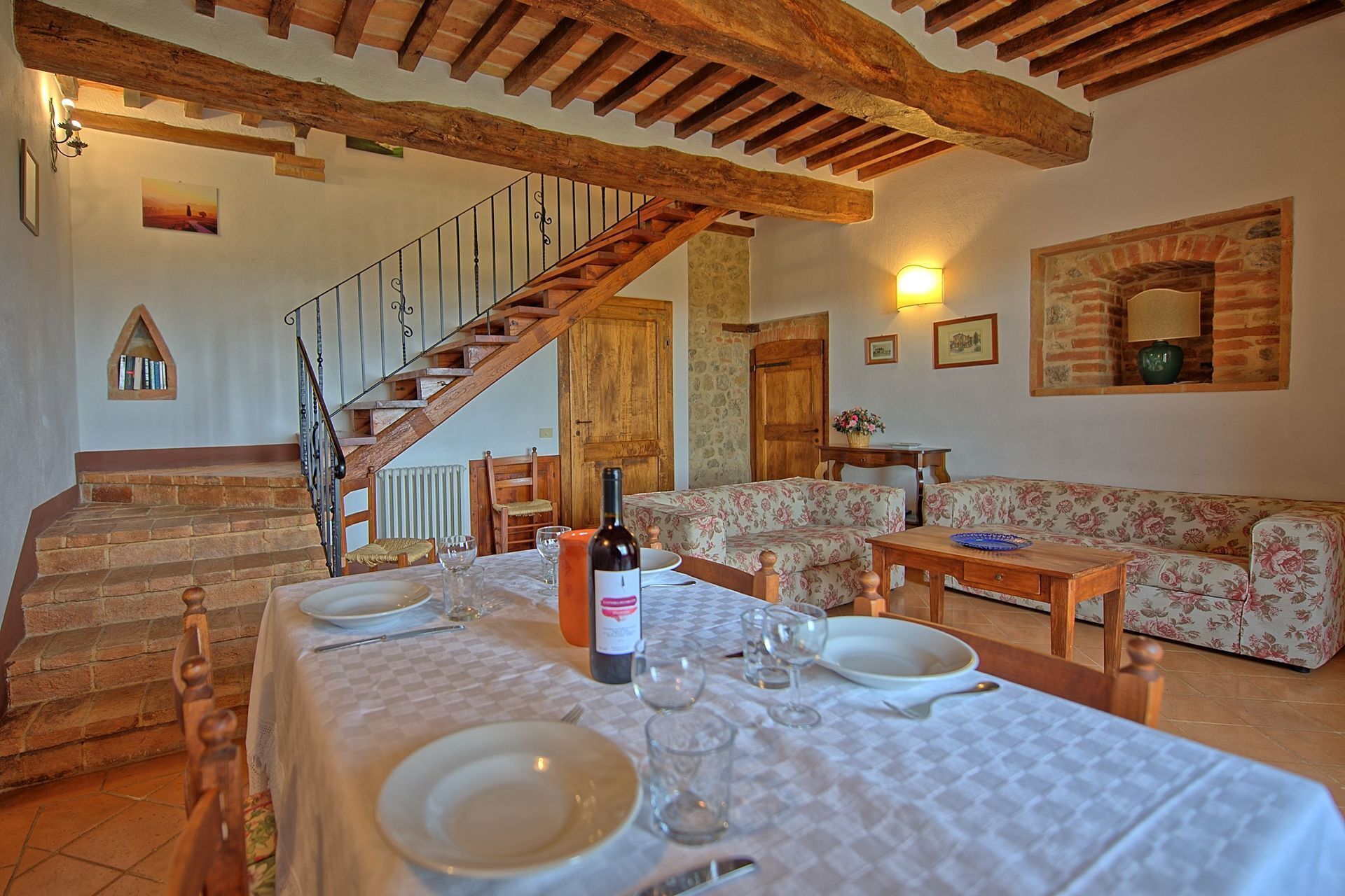Un coin repas avec un escalier en bois, un canapé et une table mise pour le repas.