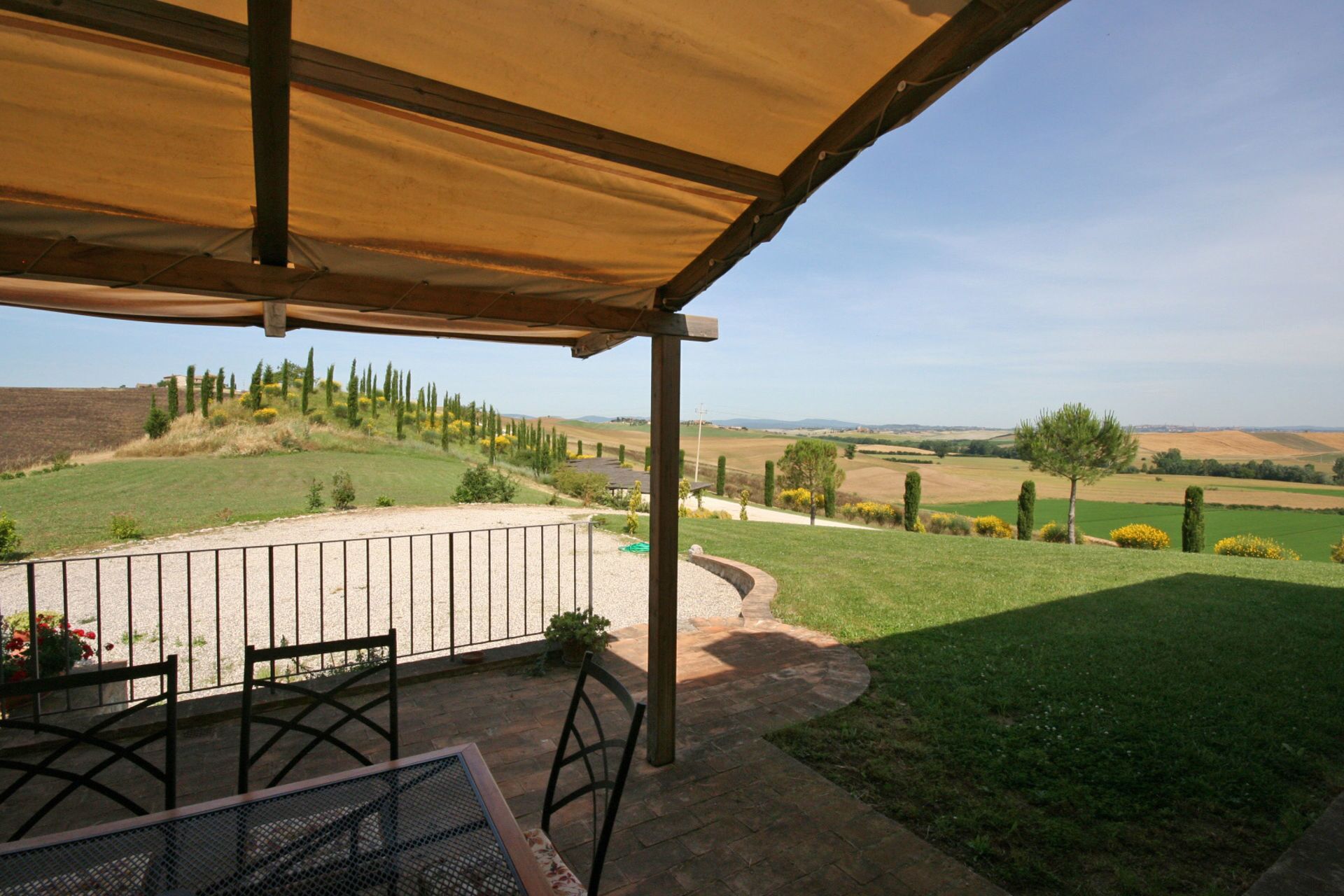 Eine überdachte Terrasse mit Blick auf sanfte Hügel und einen klaren Himmel.