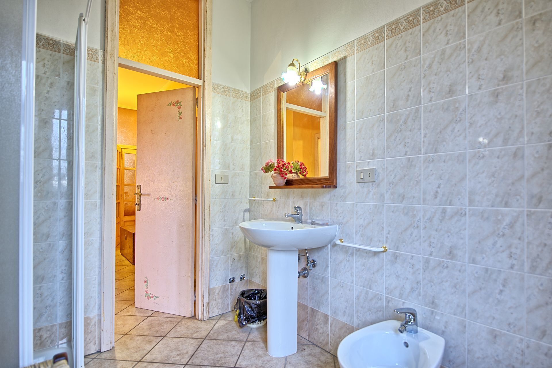 Un baño con lavamanos pedestal, espejo y bidé.