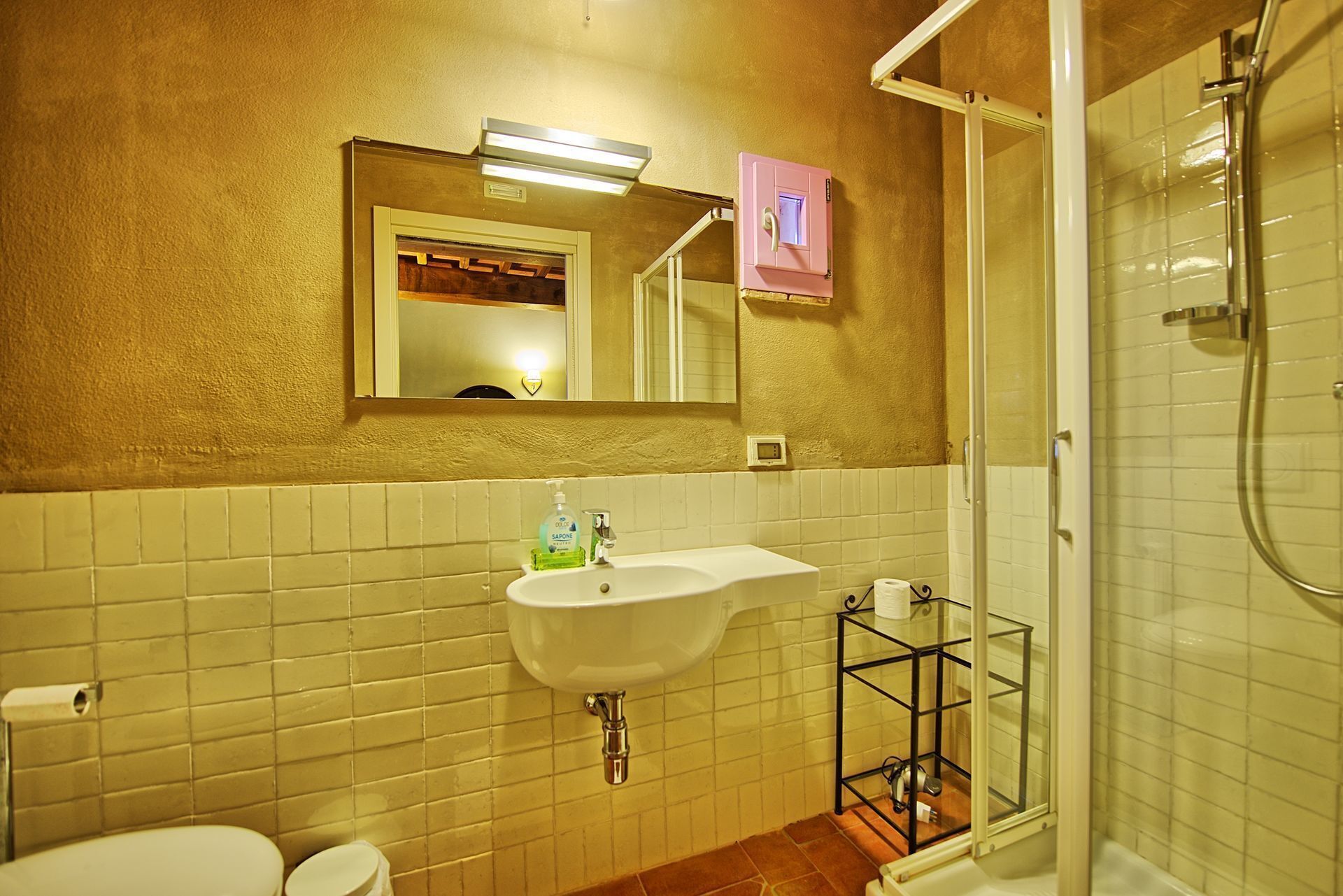 A bathroom with a white sink, a mirror, a toilet, and a shower.