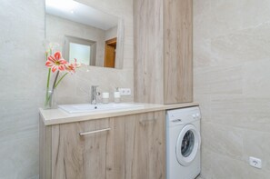 Ein modernes Badezimmer mit einem Holzlagerflansch, einem Waschbecken, einem Spiegel und einer Waschmaschine.