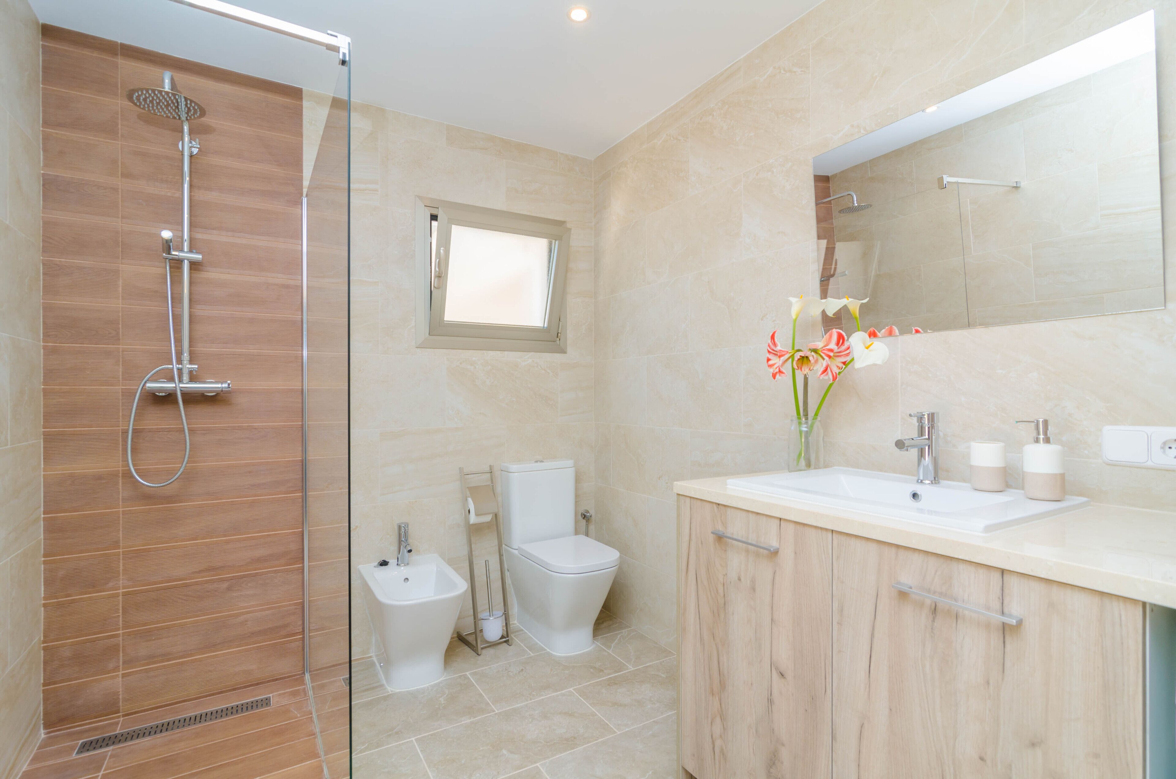Une salle de bain moderne avec une douche à parois de verre, des toilettes et un meuble-lavabo avec un miroir.