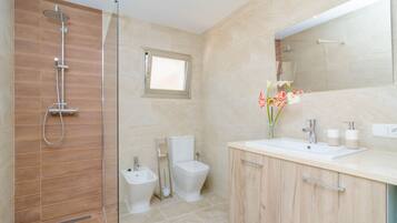 Une salle de bain moderne avec une douche à parois de verre, des toilettes et un meuble-lavabo avec un miroir.