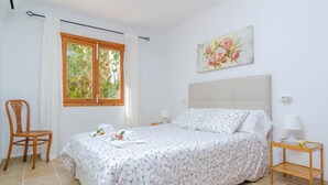 A bedroom with a bed, a chair, a window, a painting, and a nightstand. - CASA GARONDA - Beautiful chalet with private pool near the beach Free WiFi (Cala Pi)
