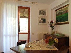 A dining area with a table set for two, a radiator, and framed photographs on the wall. - Beautiful apartment for 5 guests with pool, WIFI, TV and patio (Sassetta)