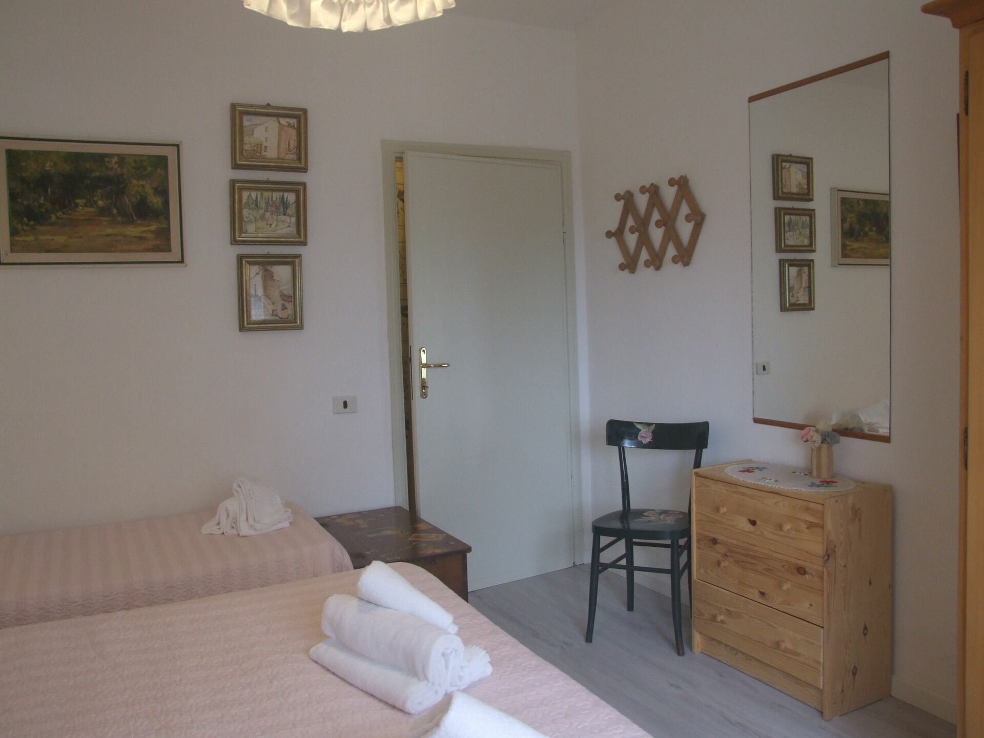 A bedroom with a bed, a chair, a dresser, and a door.