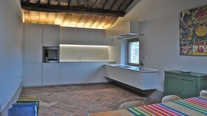 Una cocina compacta con horno integrado, ventana y un colorido cuadro abstracto en la pared.