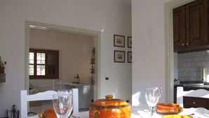 Un comedor con una mesa dispuesta para dos, con vajilla de cerámica naranja y cristalería transparente.