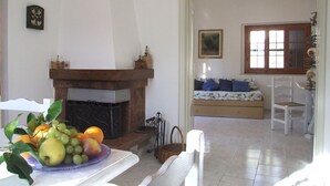 Una sala de estar con chimenea, un sofá, una mesa de comedor y un frutero.