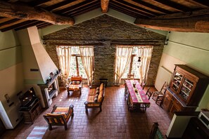 Un comedor rústico con pared de piedra, vigas de madera y suelo de ladrillo.