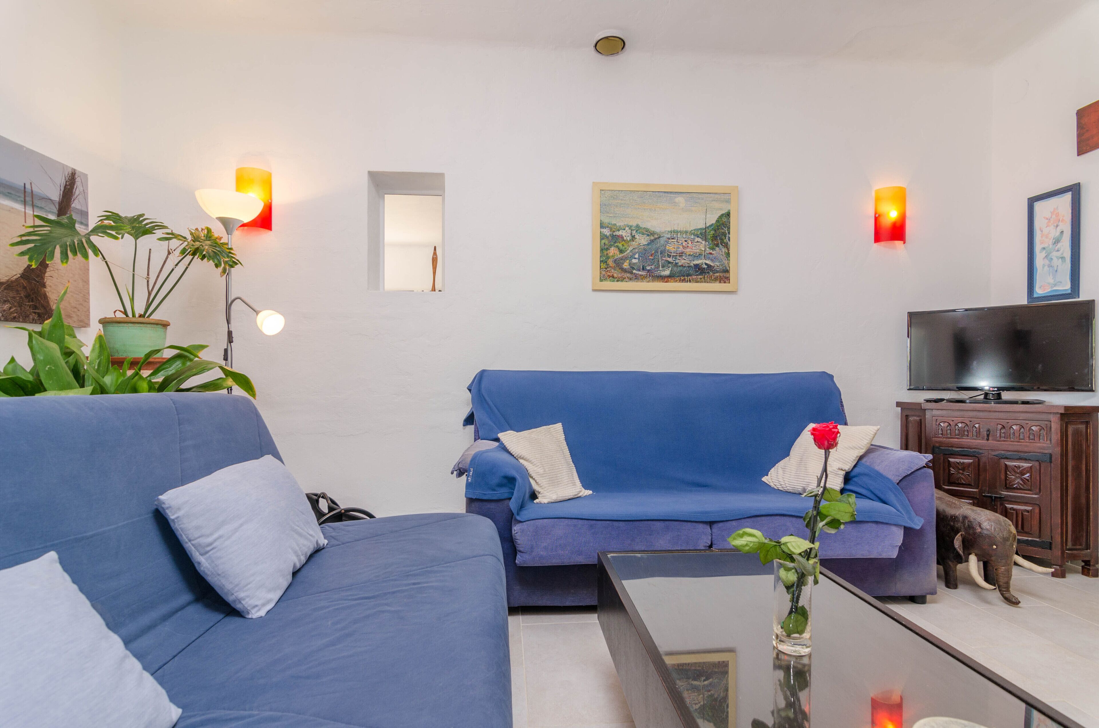A living room with a blue sofa, a coffee table, a TV, and decorative items including a rose and an elephant statue.