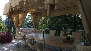 Patio esterno con tavolo e sedie rotonde, coperto da un'ampia tenda beige.