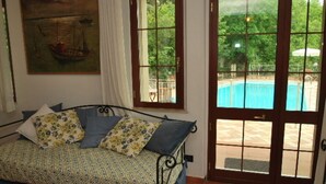 Una camera da letto con un letto, un quadro e vista su una piscina attraverso una porta in vetro.
