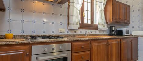 A kitchen with wooden cabinets, a stainless steel oven, a microwave, and a sink.