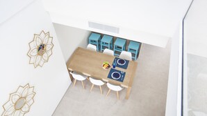 Ein Essbereich mit einem Holztisch, vier weißen Stühlen und blauen Tischen.