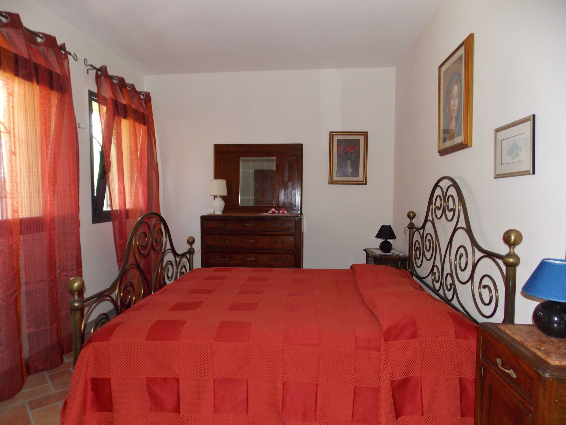 Une chambre à coucher avec un lit, une commode, un miroir et une lampe.
