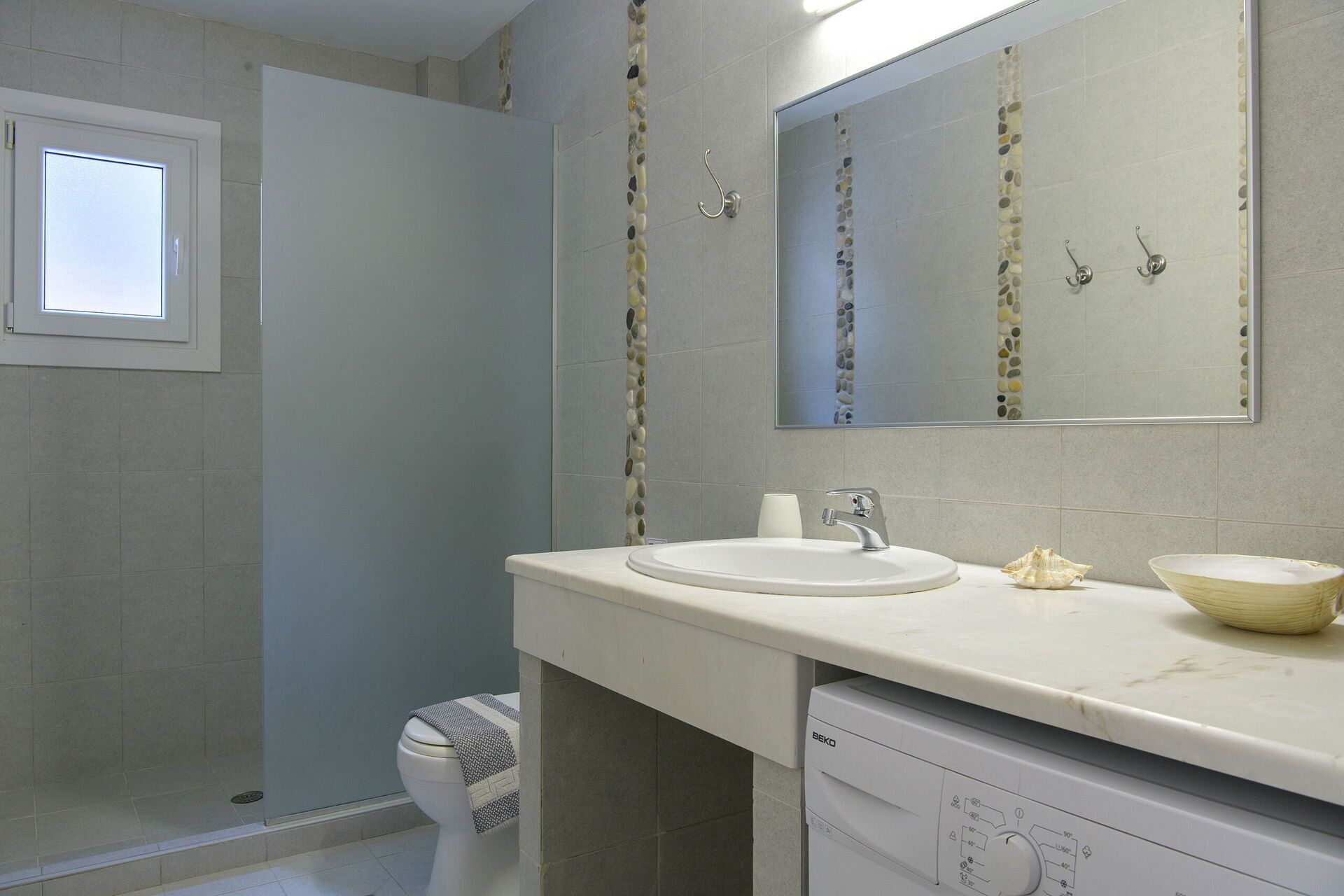 A bathroom with a white sink, a mirror, and a toilet.
