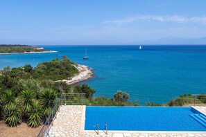 Una piscina con vistas al mar y un velero.